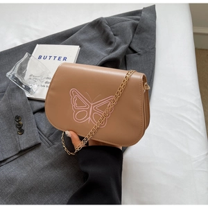 Détail d'un sac besace marron avec broderie papillon rose et chaîne dorée chic