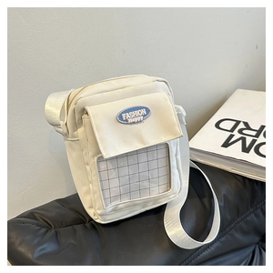 Détail du sac bandoulière en toile avec écusson bleu et poche avant en maille PVC