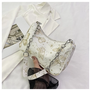 Détail de l'imprimé papillon et chaîne métallique sur le sac demi-lune crème chic