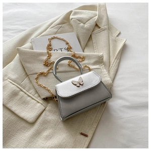 Detail of silver mini bag featuring a pearl-texture butterfly clasp and gold chain strap