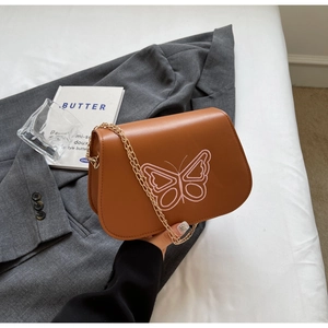Détail du sac à bandoulière en similicuir marron avec broderie papillon rose et chaîne