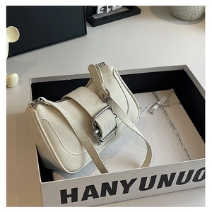 Detail view of cream white hobo bag with large silver buckle in a gift box packaging
