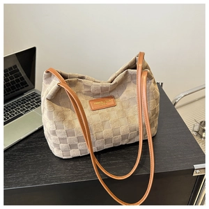 Close-up of checkered tote bag with brown leather straps on a black wooden desk