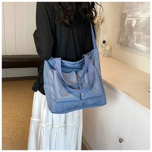 Blue Oxford tote bag with dual front pockets shown from a stylish back view perspective