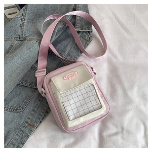 Détail du sac bandoulière en toile rose et blanc avec poche PVC et étiquette en tissu