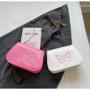 Détail de la broderie papillon et chaîne dorée sur sacs bandoulière rose et blanc