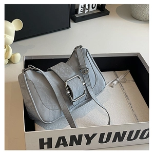 Detail of light grey blue shoulder bag with pleated texture and silver buckle in gift box