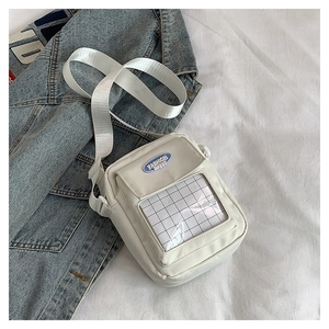 Détail du sac bandoulière en nylon blanc avec poche avant transparente et étiquette bleue