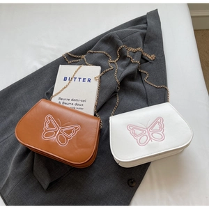 Détail de broderie papillon sur sacs à bandoulière en blanc et marron avec chaîne dorée
