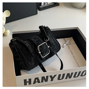 Close-up of black wrinkled texture shoulder bag with large silver buckle in a gift box