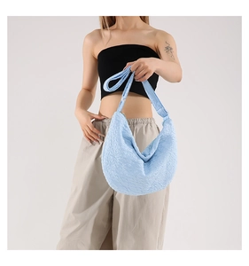 Dettaglio della borsa hobo azzurra con texture a pieghe e tracolla larga indossata