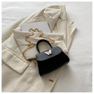 Detail of black bow-knot crossbody bag with gold chain and matte PU leather texture