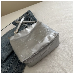 Nahaufnahme der silbernen gesteppten Ledertasche mit goldener Schnalle auf Denim-Stoff