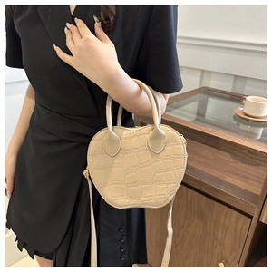 Detail of apple-shaped handbag with crocodile pattern texture and top handles