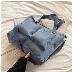 Detail of blue nylon tote bag showing dual large front pockets and smooth fabric texture