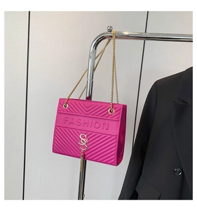 Detail der rosafarbenen Glanztasche mit FASHION-Prägung und goldener Kettenriemen