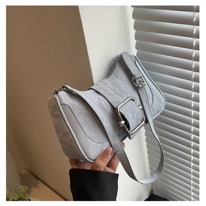 Detail view of large silver buckle on marble texture leather shoulder bag
