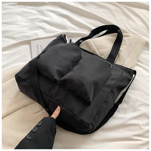 Detail of black Oxford tote bag featuring two front utility pockets and adjustable strap