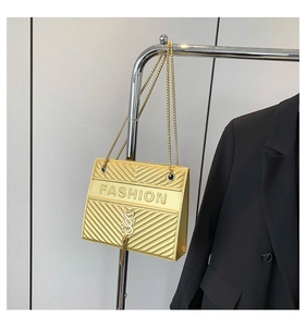 Detail der goldenen Kettenumhängetasche mit FASHION-Prägung und Metall-Quasten-Anhänger