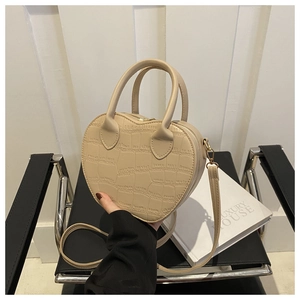 Detail of beige heart-shaped handbag with crocodile texture on a black metal chair