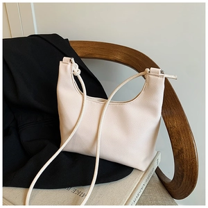 Detail of the knotted shoulder strap and pebbled leather texture on an ivory tote bag