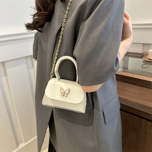 Chic white mini square bag with pearlescent bow clasp and golden chain strap