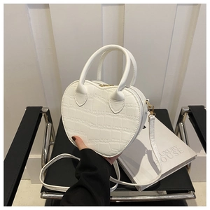 Close-up of white heart-shaped handbag with crocodile embossed texture and metal zipper