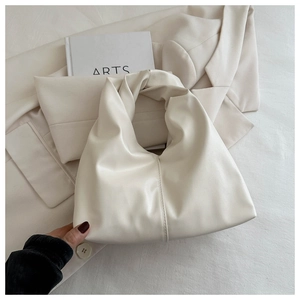 Close-up of cream white tote bag with knotted handle detail and soft pleated texture