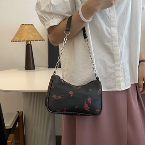 Black shoulder bag with red floral print and silver chain strap shown on a model