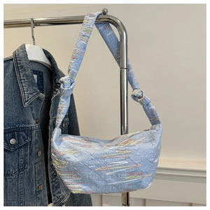 Detail of light blue dumpling bag featuring geometric texture and rainbow embroidery