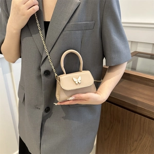 Elegant beige crossbody mini bag with bow-shaped metal clasp and golden chain strap