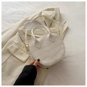 Detail of white crocodile-embossed heart-shaped handbag on a chic beige blazer