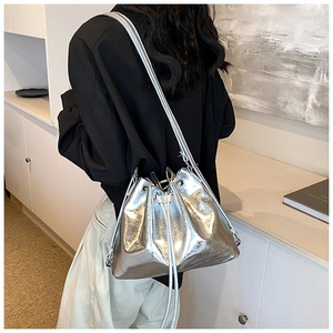 Silver metallic bucket bag with drawstring closure shown on model in modern interior