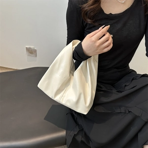 Minimalist cream white slouchy tote bag in soft leather shown on shoulder for daily commute
