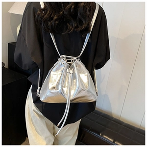 Modern metallic silver bucket bag shown worn by a model in a minimalist setting
