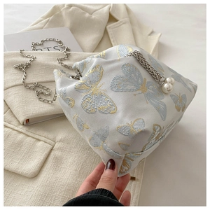 Detail of embroidered butterfly jacquard bag with silver chain and pearl charms