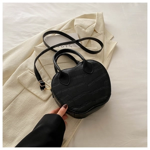 Detail of black apple-shaped tote bag with crocodile pattern on a white blazer