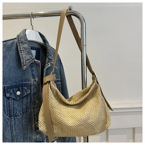 Detail of hand-woven straw hobo tote with adjustable light brown leather shoulder strap