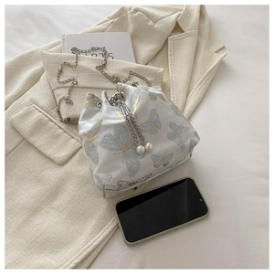 Detail of a drawstring bucket bag with light blue butterfly embroidery and pearl charm