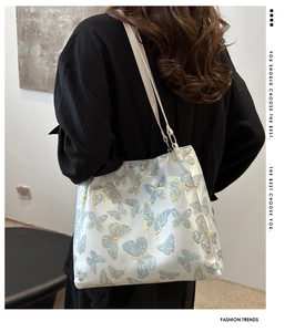 Detailed close-up of golden embroidery butterflies on a light satin shoulder bag