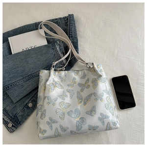 Detail of bamboo butterfly embroidery on white underarm bag with silver hardware