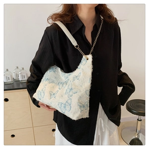 Détail du sac cabas en toile blanche avec imprimé papillon bleu et chaîne en métal