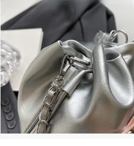 Gros plan d'un sac bandoulière argenté en cuir texturé avec chaîne et fermoir mousqueton