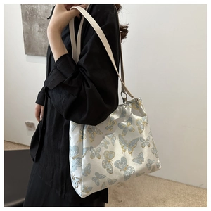 Detail of white shoulder bag featuring delicate light blue and gold butterfly embroidery
