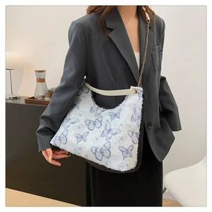 Détail du sac cabas avec imprimé papillon bleu et bandoulière en chaîne dorée