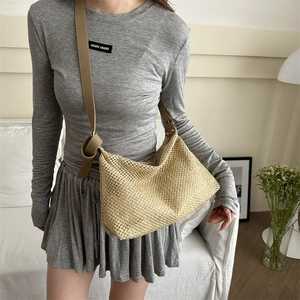 Handwoven beige straw tote bag with brown leather strap in a stylish casual setting