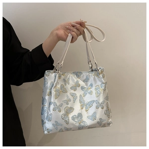 Detailed view of delicate butterfly embroidery and silver rings on light blue satin bag