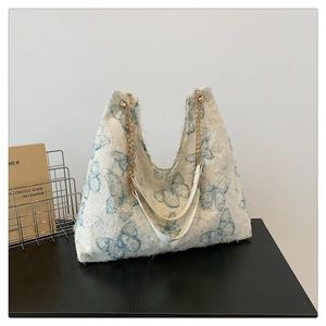 Gros plan du sac cabas en peluche blanche avec papillons bleus et bandoulière chaîne