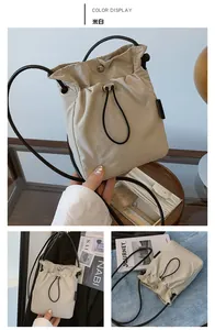 Detail view of cream drawstring bucket bag with black strap and metal adjustment buckle