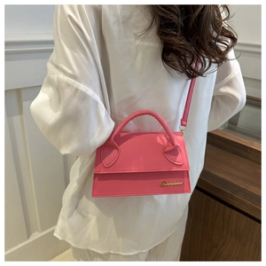 Hot pink mini leather handbag with gold logo detail worn by model in a stylish setting